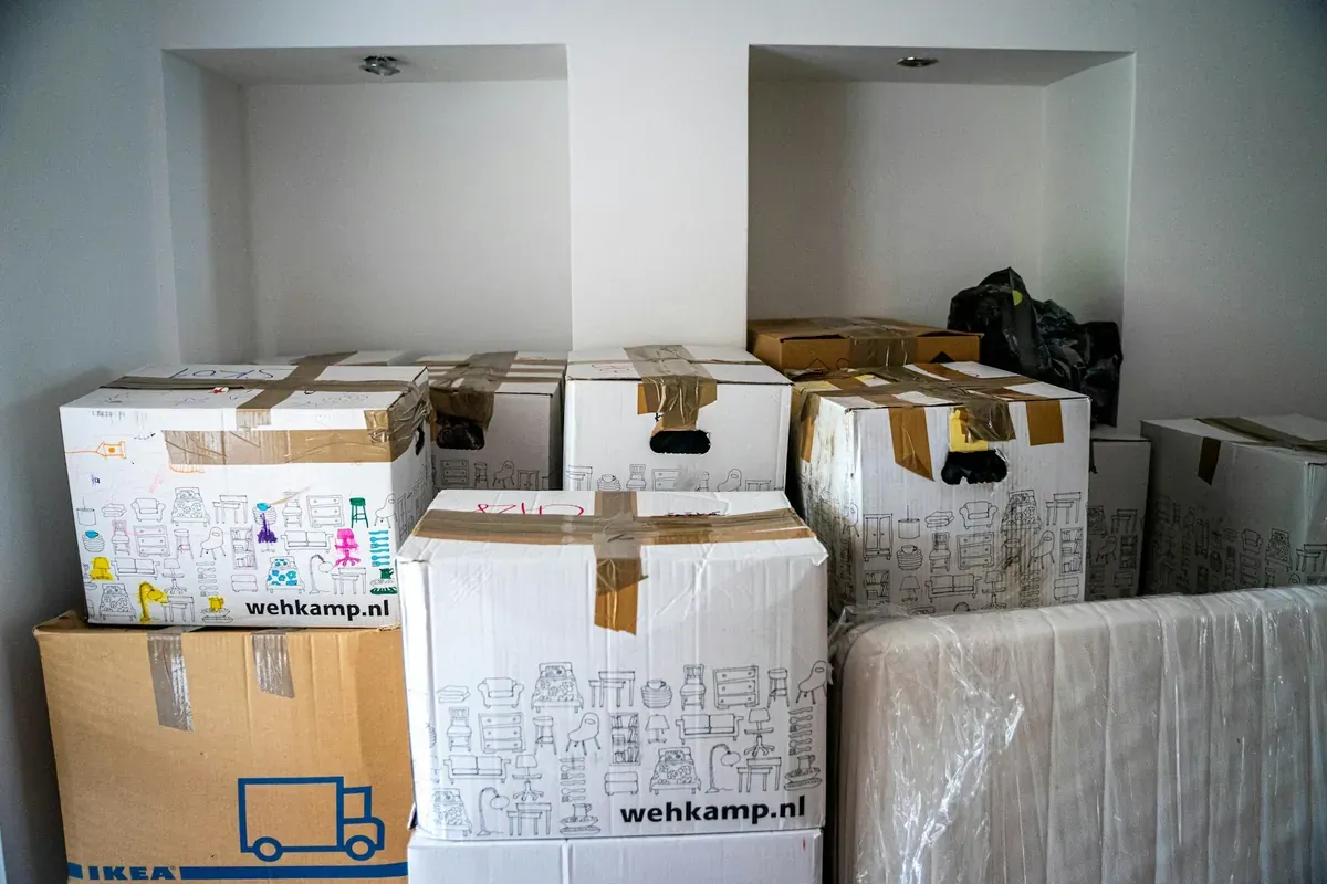 Packed moving boxes and a wrapped household item gathered in a room.