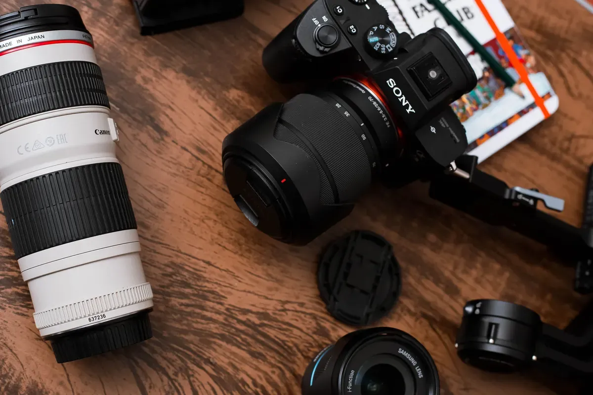 Cameras and lenses on a wooden table, with identifying markings visible on a lens.