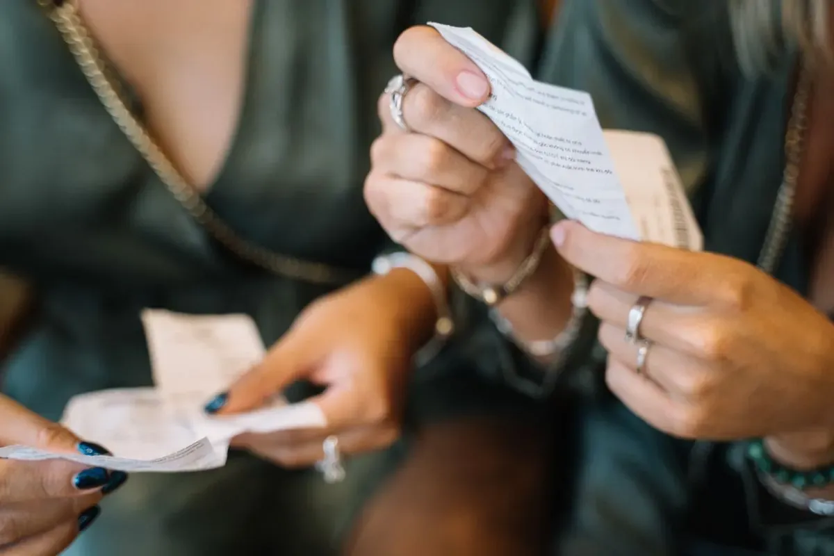 Two people comparing paper receipts by hand.
